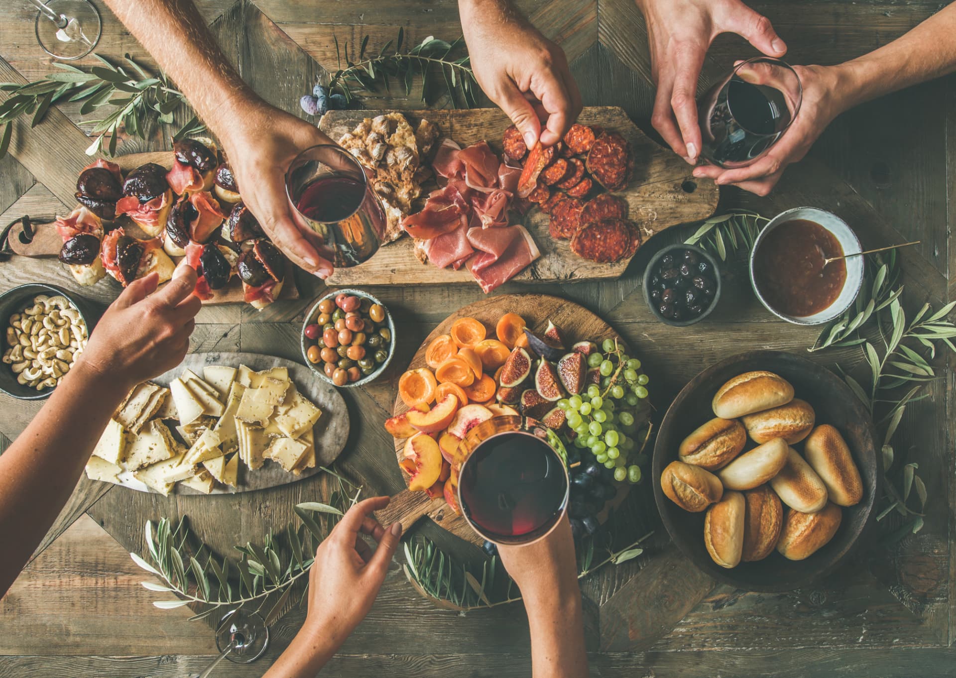 Apéro-Tafel von oben mit Vorspeiseplatten, Früchten, Brot und Weingläsern
